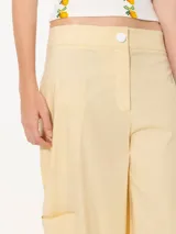 Pantalón cargo color amarillo claro, confeccionado en poplin asargado. Tiene cuatro bolsillos plaqué con refuerzos triangulares en hilo crudo. El ruedo lleva jareta para ajustar y abuchonar con lazo.