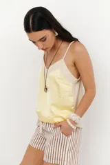 Musculosa de tirantes delgados con diseño bicolor: la parte superior es de color crema y la parte inferior es de color rosado pálido, ambas con acabado satinado.