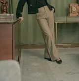 Pantalón de cuerina color beige, de corte recto y tiro alto, con cierre y broche escondido.