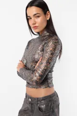 Top manga larga plateado con detalles perforados, semi polera y terminaciones al corte.