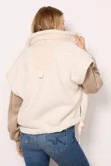 Chaleco de piel sintética tipo sherpa en color blanco crema, con cuello alto y cierre frontal mediante botones a presión. Presenta un diseño de hombros caídos y detalles de lazos decorativos en los laterales inferiores.