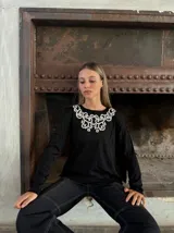 Remera blanca de manga larga con cuello redondo y bordado floral en el pecho.