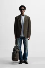 Blazer straight fit color marrón oscuro con finas rayas verticales claras. Confeccionado en tejido con lana de origen italiano. Cuello con solapas de muesca y manga larga acabada en puño con botones. Bolsillos de vivo en pecho y de solapa en cadera. Detalle de bolsillo interior. Bajo con aberturas en espalda. Cierre frontal de botonadura.