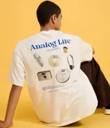 Remera de algodón blanca, corte oversized, con estampa gráfica en la espalda que incluye un teléfono antiguo, un CD, una cámara fotográfica, auriculares y un reproductor de CD portátil, junto al texto "Analog Life - NO EDITS -".