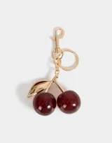 Llavero con dije de cerezas rojas con glitter y hojas doradas, con mosquetón metálico dorado.