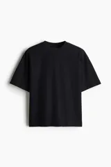 Remera negra de punto de algodón pesado, corte oversized, con cuello redondo ribeteado, hombros caídos y bajo recto.