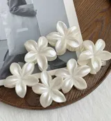Pinza para el pelo con forma de flor de cinco pétalos color blanco nacarado.
