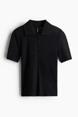 Remera polo corta negra de punto fino acanalado, entallada, con cuello clásico, tapeta de botones y mangas cortas.
