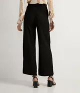 Pantalón negro tipo pantalona en viscosa y lino, con pliegues, trabillas y cinturón con hebilla.
