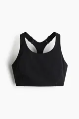 Top deportivo negro de soporte alto, confeccionado en tejido funcional ShapeMove™ y DryMove™. Cuenta con copas forradas con relleno extraíble, breteles anchos ajustables, espalda nadadora de malla y cierre de corchetes.