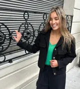 Chaqueta corta negra de lana y viscosa, con cuello clásico, cierre frontal con botones y bolsillos de parche en el pecho.
