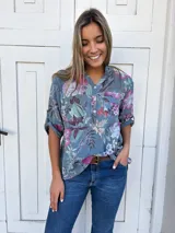 Camisa de cuello mao con estampado floral sobre fondo celeste y mangas 3/4 con trabilla.