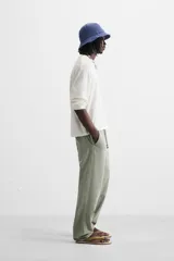 Pantalón color arena de corte recto, confeccionado en tejido de algodón y lino. Cuenta con cintura elástica ajustable con cordón, bolsillos delanteros y traseros de parche.