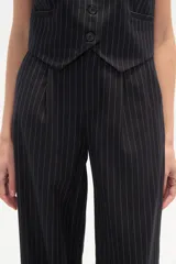 Pantalón de poliéster negro con rayas verticales blancas, de corte recto y tiro alto.