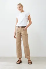 Pantalón recto color tostado con pespuntes verticales y cinturón de cuero marrón con hebilla dorada.