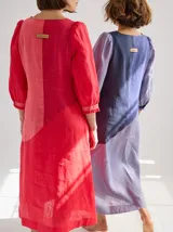 Vestido midi de lino color lila con escote en V y mangas 3/4 abullonadas con puño elástico. Presenta paneles laterales en denim y costuras a la vista en color rojo.