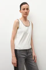 Top sin mangas color crudo, de corte recto, con escote redondo y detalle de pespunte negro alrededor del cuello y el ruedo.