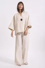 Blusa color crema de lino, de corte holgado, con cuello en V, mangas anchas y un botón grande negro.
