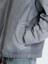 Campera azul grisáceo con cuello clásico de cuero negro, cierre frontal con cremallera, manga larga, puños con botón a presión, dos bolsillos laterales con solapa y un bolsillo interior.