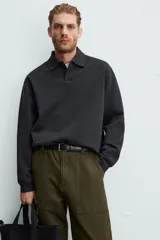 Polo manga larga negro de algodón con elasticidad y estructura. Cuello solapa con cierre frontal de botonadura y acabados con rib.