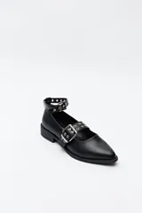 Zapato tipo zueco negro charol con punta fina, doble tira con hebillas metálicas y pulsera al tobillo con tachas.