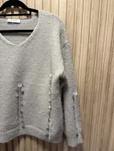 Sweater de punto color gris claro, con escote en V y detalle de lentejuelas bordadas.