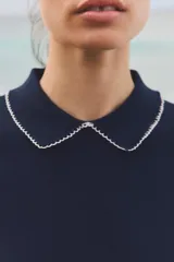 Top de punto blanco con rayas horizontales azul marino, cuello solapa y manga corta.