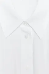 Camisa rosa claro confeccionada en hilatura con modal, de corte holgado, con cuello solapa, manga larga terminada en puño, dos bolsillos con solapa en el delantero y cierre frontal con botones.