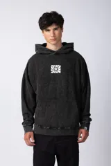 Buzo canguro negro con efecto gastado y estampa cuadrada con diseño abstracto en el pecho. Corte oversize con capucha y puños ajustados.