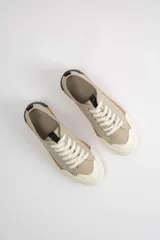 Zapatillas acordonadas color beige con suela marrón y puntera blanca.