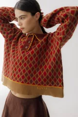 Sweater de punto color beige con diseño de rombos marrones, cuello polo con botones y mangas largas abullonadas.