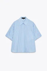 Camisa celeste con rayas verticales blancas, de corte holgado, cuello solapa, manga corta con dobladillo y bolsillo de parche en el pecho.