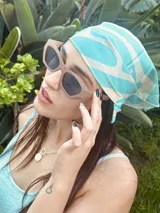 Pañuelo cuadrado de tela satinada color celeste con estampado de líneas curvas blancas.