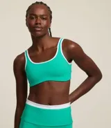 Top deportivo verde esmeralda de microfibra con breteles anchos y copa desmontable. Presenta detalles contrastantes en blanco en los bordes y escote en V en la espalda.