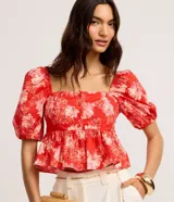 Blusa peplum cropped de tricolina con estampa floral, escote cuadrado, mangas abullonadas cortas y botones delanteros.