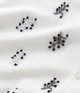 Camisa de manga corta para hombre, corte boxy, color blanco con cuello bowling y un estampado repetitivo de figuras geométricas negras.