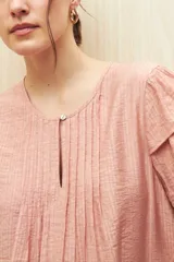 Blusa blanca de tela liviana con mangas cortas con volados y botón de nácar.