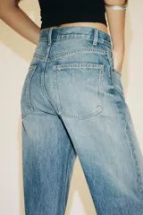 Pantalón de jean azul oscuro, de tiro alto, corte wide leg y largo hasta el tobillo.