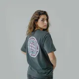 Remera blanca de algodón con estampa circular en la espalda con un globo terráqueo en color lila y texto "Bad Decisions Club Member" en negro y celeste.