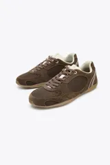 Zapatillas deportivas marrones con detalles en gamuza y malla, cordones marrones y suela beige.
