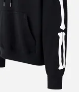 Buzo negro de fleece con felpa, corte boxy, capucha con cordón ajustable, manga larga, estampa lettering frontal, bolsillo canguro, patch de esqueleto en la manga y puños ajustados.