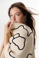 Ruana color marrón con flecos y bordados en el contorno.