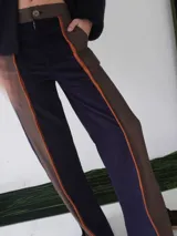 Pantalón de paño combinado con tira de cuero color naranja en los laterales.