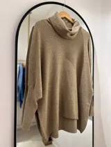 Polerón color camel de corte oversize, con cuello drapeado y mangas largas caídas. La parte delantera es más corta que la trasera.