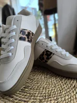 Championes blancos de cuero sintético con cordones y estampado animal print de leopardo en los laterales.