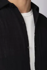 Camisa de lino blanca de manga larga, con cuello clásico y cierre frontal con botones. Corte recto y holgado.