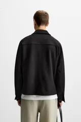 Sobrecamisa color beige de corte recto, con cuello solapa, manga larga con puños abotonados, cierre frontal abotonado, bolsillos de parche con solapa en el pecho y bolsillos de ojal en la cadera.