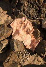 Camisa de lino a rayas verticales color naranja y blanco, de manga corta y corte oversize. Presenta bordados con motivos playeros en el frente y la espalda.