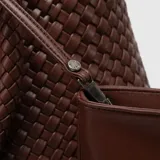 Bolso tote color marrón con diseño trenzado y doble asa de hombro. Incluye un estuche interior desmontable con cierre.