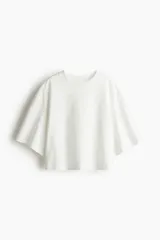 Remera blanca de corte holgado, cropped, con cuello redondo acanalado y hombros caídos.